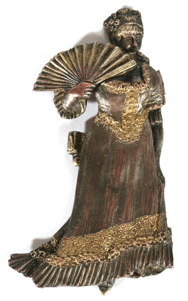 EROTIC EDWARDIAN LADIES SCARF SLIDE: In silver plate with gilt and copper tinting. This full figure of a prim and proper Edwardian lady in full evening gown holding a fan. The gown is on hinges that opens to reveal her nude except her st