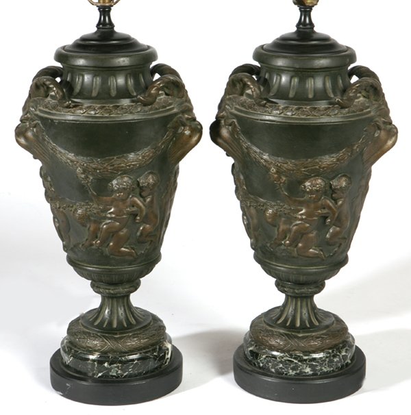 PR. OF TRETA, PARIS BRONZED URN LAMPS: Greek form vases mounted as lamps, with ram mask handles, body with high relief frolicking putti, and swags, base with laurel wreath on green veined Italian marble, and added ebonized wood for lamp mo
