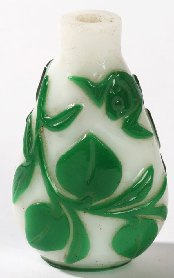 CHINESE PEKING GLASS SNUFF BOTTLE: Green cut to white jade with bats flying above peaches of immortality. Lacking stopper, otherwise fine condition. 3" h.