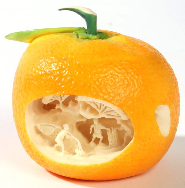 CARVED IVORY ORANGE WITH VILLAGE SCENE: A very life like orange, carved from a single piece of ivory, with deeply carved village scene on interior with figures, trees, and buildings. Fine condition. 2 1/2" h. x 2 1/2" w. THIS LOT CANNOT BE