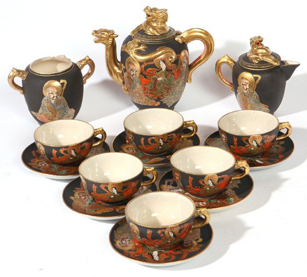 JAPANESE ROYAL SATSUMA TEA SET: Nine pieces with teapot, creamer, sugar, and six cups and saucers. All hand painted with figures and relief dragons in gilt. All marked on base. One chip on lid of pot and sugar missing lid. Teapot 15