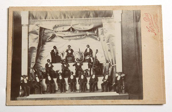 RARE CABINET CARD OF BLACK MINSTREL DIORAMA: With imprint of Hern Bros. N.Y. showing a miniature stage set with 16 member African American Band with the name of the band on bass drum reading “The Georgia Minstrel.”