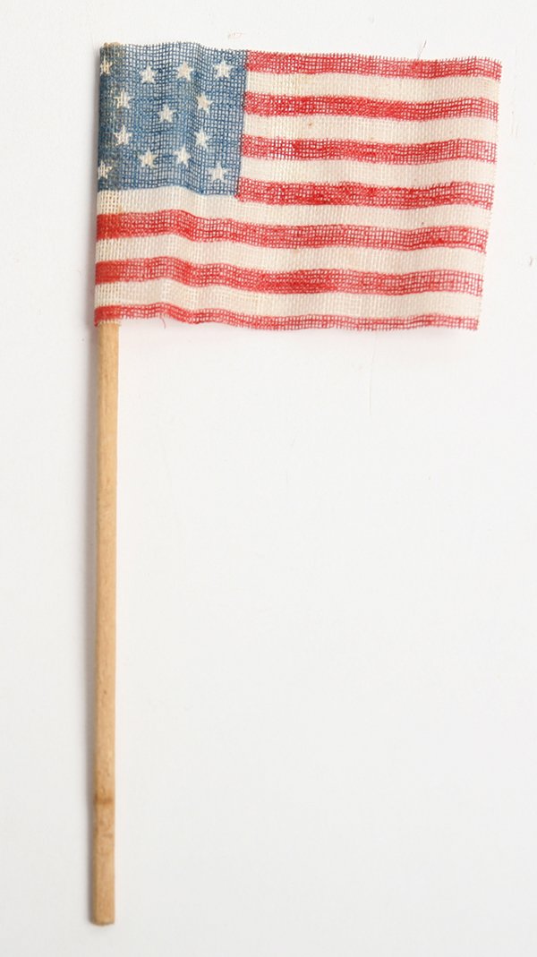LINEN 13 STAR U.S. CENTENNIAL PARADE FLAG: Printed with canton having central star surrounded by ring of stars and four in corners, mounted on original wood stick, 2” x 3”; stick is 6” long.