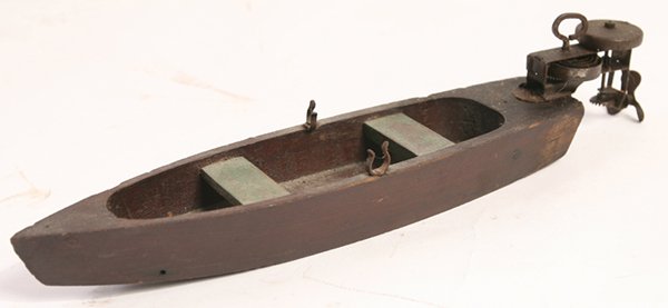 WONDERFUL WINDUP TOY FISHING BOAT: In original varnished and painted wood with cast iron oar locks and tin spring driven outboard motor attached to stern, 12” long, working.