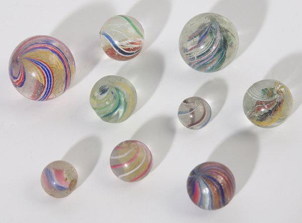 9 HAND MADE MARBLES: Includes a very nice mica swirl onionskin (1.5cm), four latticino swirls, 1”, (2.2cm) & 0.65”, (1.25cm), & 0.7”, (1.5cm) & 0.7”, (1.5); and others.