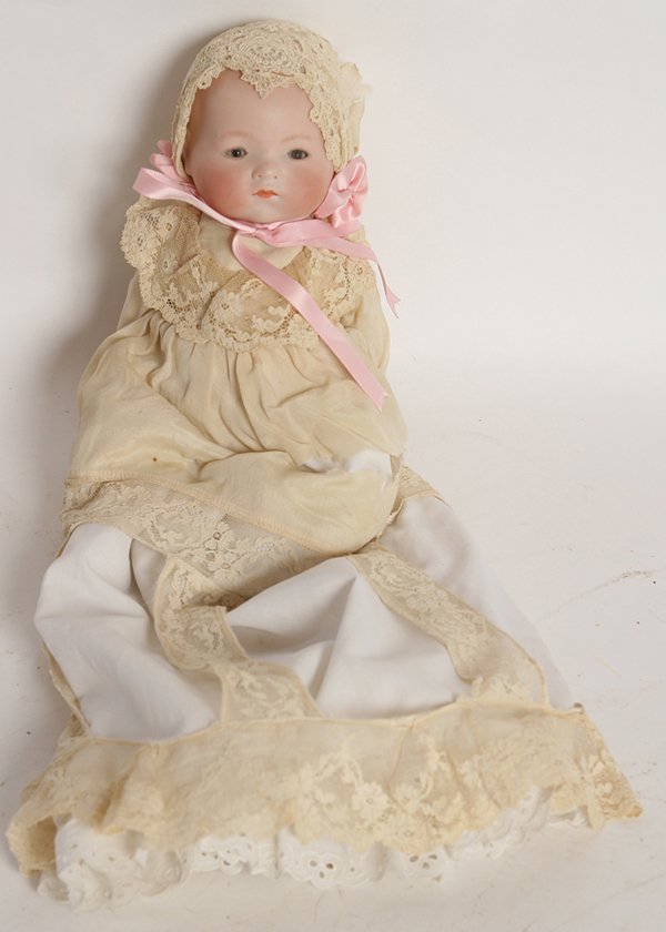 A.M. DREAM BABY BISQUE DOLL: Domed head marked on back of head “A.M. Germany” with sleep brown glass eyes, painted hair, closed mouth, on cloth body with bisque hands, in original white gown and bonnet, 11” tall.