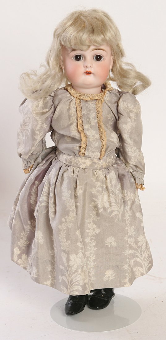 KESTNER BISQUE CHILD DOLL: Socket head with sleep brown glass eyes, open mouth, marked on back of head “D. Made in Germany” with original blond wig, on ball jointed composition body in period faded purple flowered dress wit