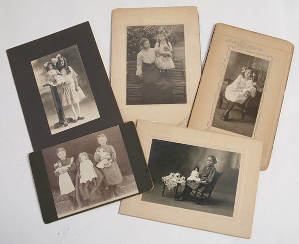 EARLY PHOTOS OF GIRLS & THEIR DOLLS: Lot of 5, all on period card stock mounts, early silver gelatin prints, circa 1890’s to 1920’s. Includes a cute 4” x 6” on larger mount of little girl seated in rocking chair with her German b