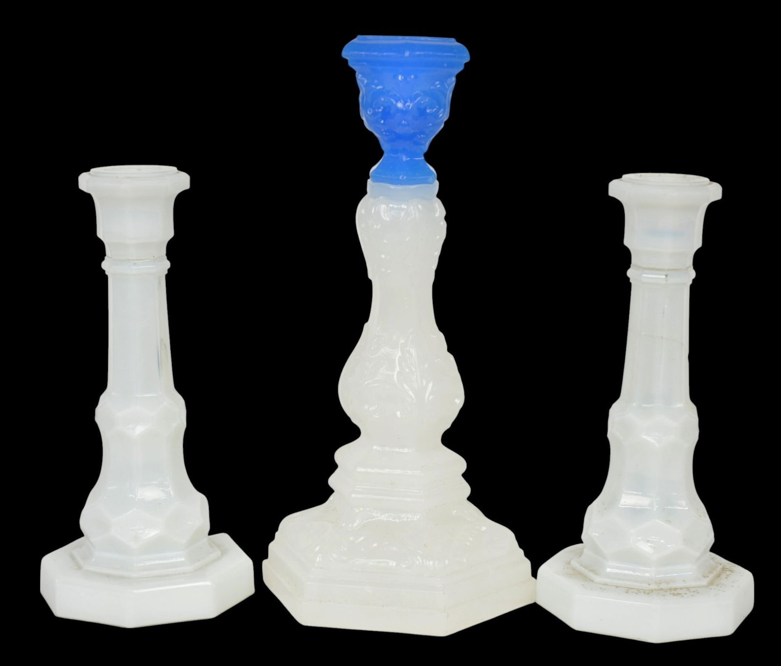 Three Sandwich Candlesticks: One with sapphire blue candlesocket and hexagonal base, both with scrolled floral relief, 4.8" diameter x 9.25" high; plus paint of opalescent faceted sticks with hexagonal form, 3.2" diameter x 7" hi