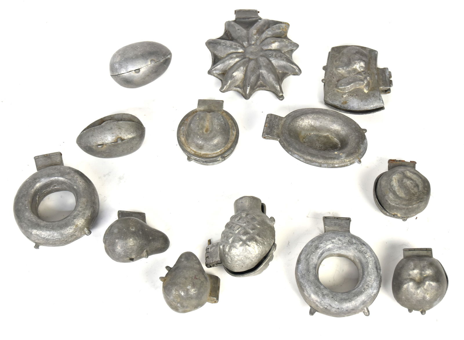 Thirteen Pewter Ice Cream Molds: Including two wreaths, pointset flower, two different eggs, two pears, quintz, pineapple, rose, and more, several marked, most circa 3-4". Condition one missing hing pin.