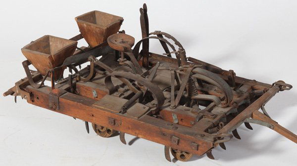 PATENT MODEL OF HORSE DRAWN PLANTER: In hand carved wood and steel with chisel type plows on underside that can be raised or lowered by levers next to the drivers seat. Another lever opens seed hoppers, 9" wide x 8.5" high x 24" long. Ci