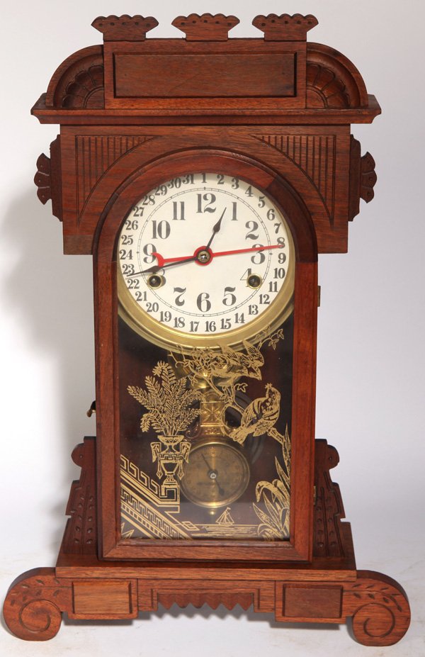 NEW HAVEN CALENDAR CLOCK: In walnut case with geometric carvings and scroll feet, original gilt tablet with birds on branch and potted fern, printed paper over tin dial with brass surround, brass time, strike & date spring dri