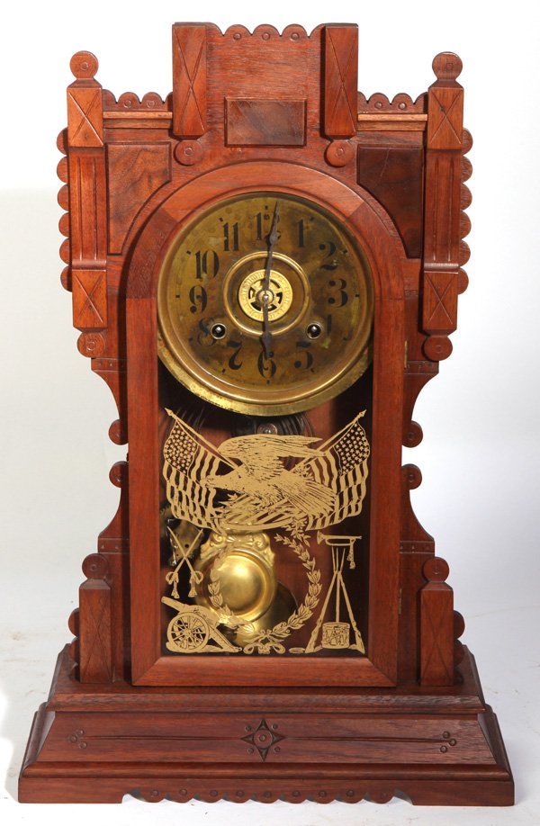 NEW HAVEN LIFFEY KITCHEN CLOCK: In walnut case with geometric carvings, original gilt tablet with patriotic motifs, dark paper over tin dial with brass surround and cast brass alarm wheel in center marked “Made By The New Haven Cl