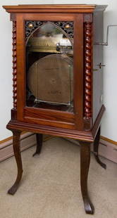 REGINA 15 1/2" AUTOMATIC DISC CHANGING MUSIC BOX: Double comb. Fine mahogany case with rope twists & iron legs. 12 discs. 61" high x 25" wide x 20 1/2" deep.