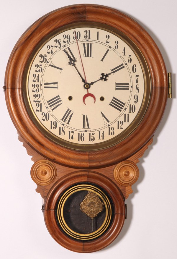 LOVELL MFG. CO. HANGING CALENDAR CLOCK: With painted steel dial with brass bezel surround, reverse figure 8 shape with original painted lower tablet, brass spring driven time, strike & date movement, original pendulum and key with printed l