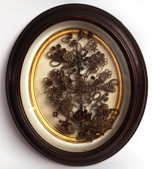 FRAMED VICTORIAN MEMORIAL HAIR WREATH: Made from hair with wire tree covered with woven hair flowers and buds of various types, some died red and yellow, others bleached white or silver, set in a wonderful walnut oval shadow box frame with