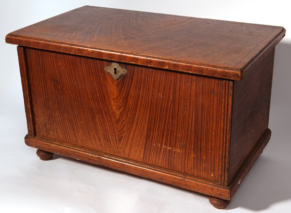 MINIATURE GRAIN PAINTED BLANKET CHEST: Circa 1860 with dovetailed case, overhanging lid with breadboard ends, fluted corner molding and cove molded base on turned bun feet. Interior with original wrought iron lock and lidded till, 25.5 x 1
