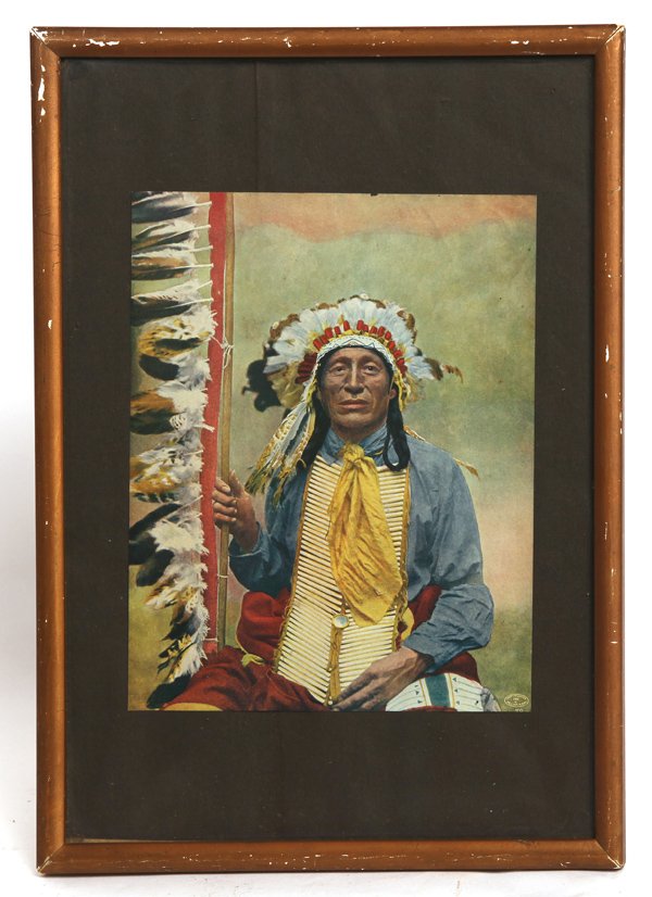 REINHART PHOTO OF SIOUX CHIEF: Colored photogravure of a Sioux warrior with feathered spear, tubular beaded breast plate, full eagle feather headdress with beaded pipe bag over left leg, marked in lower right corner “Copyrighted/