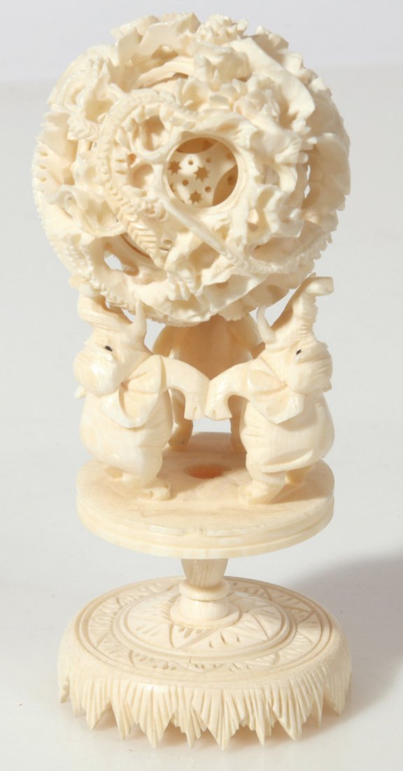CARVED CHINESE IVORY MYSTERY BALL & STAND: With 2”diameter ball carved with dragons, with six inner spheres and stand with three elephant standing on hind legs holding ball in tusks and trunks, total height 5.5”. THIS LOT CANNOT BE SHIPPED