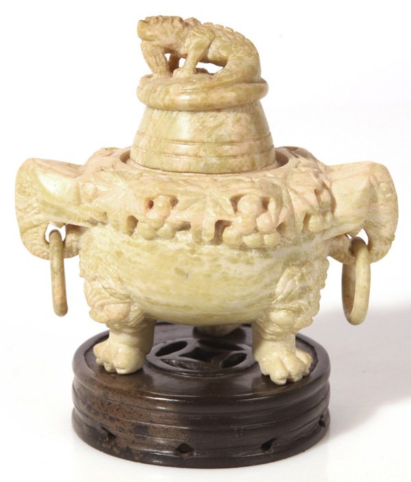 CARVED STEATITE CHINESE CENSOR: In light green with dragon finial on lid, elephant mask handles with free swinging ring handles, claw feet with cat mask above and relief carved vintage pattern around lip, on a carved dark brown stea