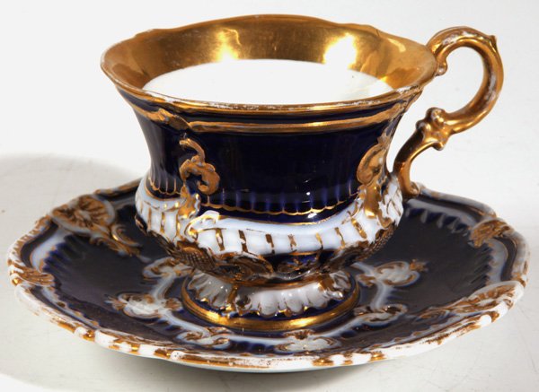 MEISSEN CUP & SAUCER: In relief shell scrolls decorated in cobalt and git with blue underglaze crossed sword mark on each and impressed numbers, saucer is 6”diameter and cup is 3”high.
