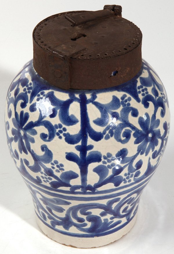 IRON MOUNTED 18TH CENTURY APOTHECARY JAR: In blue underglaze stylized floral painting on faience body, wonderful hand wrought iron cap with lock and stylized floral engraving, circa 1720-40, probably English, 8”diameter x 12”high.