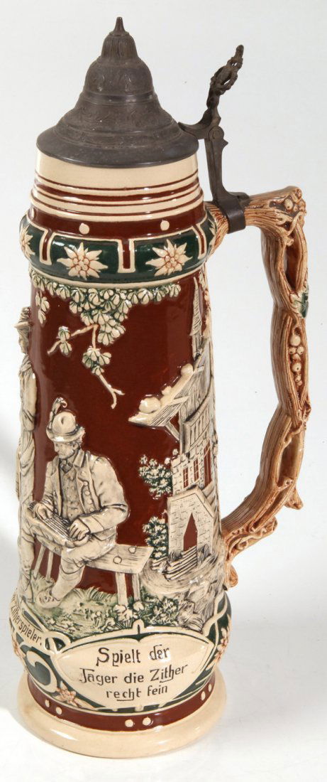 LARGE GERMAN STONEWARE STEIN: In high relief, circa 3 liter size with older gentleman playing zither while two young ladies watch with inscriptions in German and alpine style building in background, domed pewter lid with thumb lif
