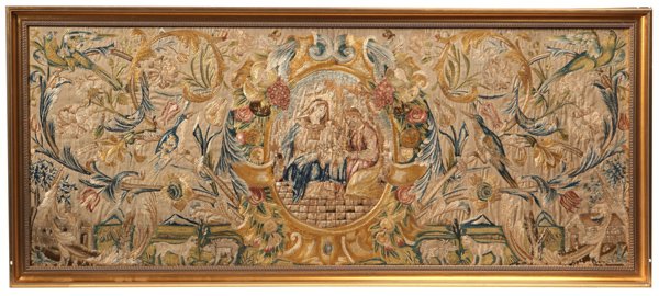 Large 18 th Century Needlepoint Picture: Circa 1750 showing central oval portrait of the holy family, surrounded by a beautifully embroidered scrolled wreath of fruit and flowers, surrounded by landscape of vining flowers with birds in fligh