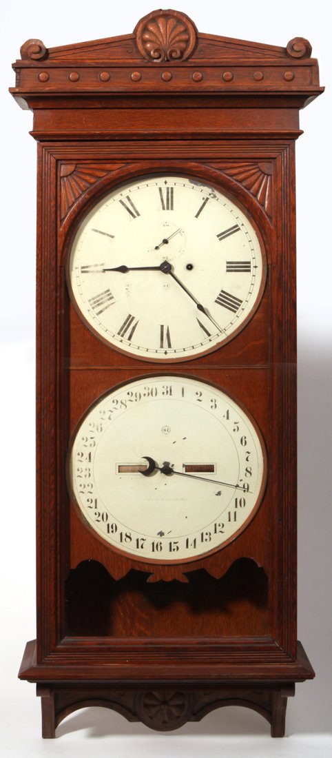 Seth Thomas #13 Oak Calendar Wall Clock: With case in original varnish finish, shell and scroll carved pediment and lower drop, arched door with carved fans in corners, steel dial in original painted finish with second hand dial above center