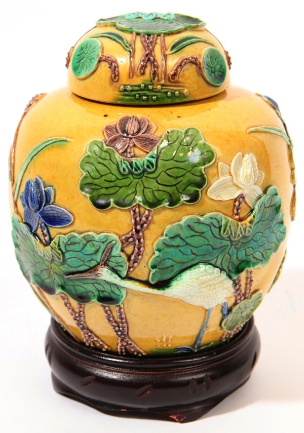 Carved Chinese Ginger Jar: Porcelain with yellow ground and beatuifully carved lilly pads painted in green, brown and blue, 5.5" high with 1.25" high carved teak stand.