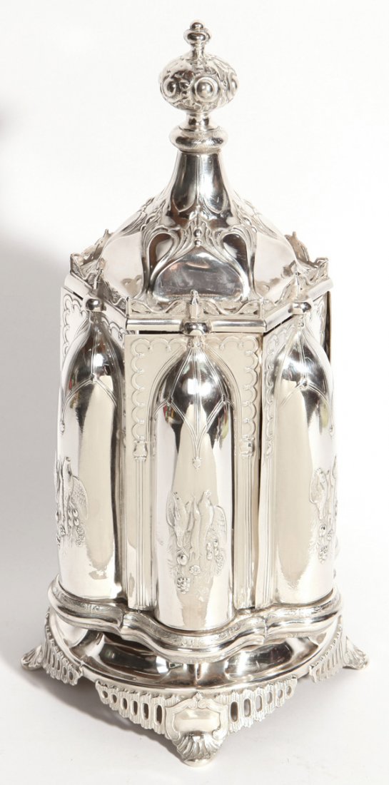 Ornate Victorian Plated Cruet Stand: On revolving base with knob that opens compartments for six bottles, decorated with relief hanging game and fish with ornate finial and shell scroll feet, crest type makers mark on base, likely Englis