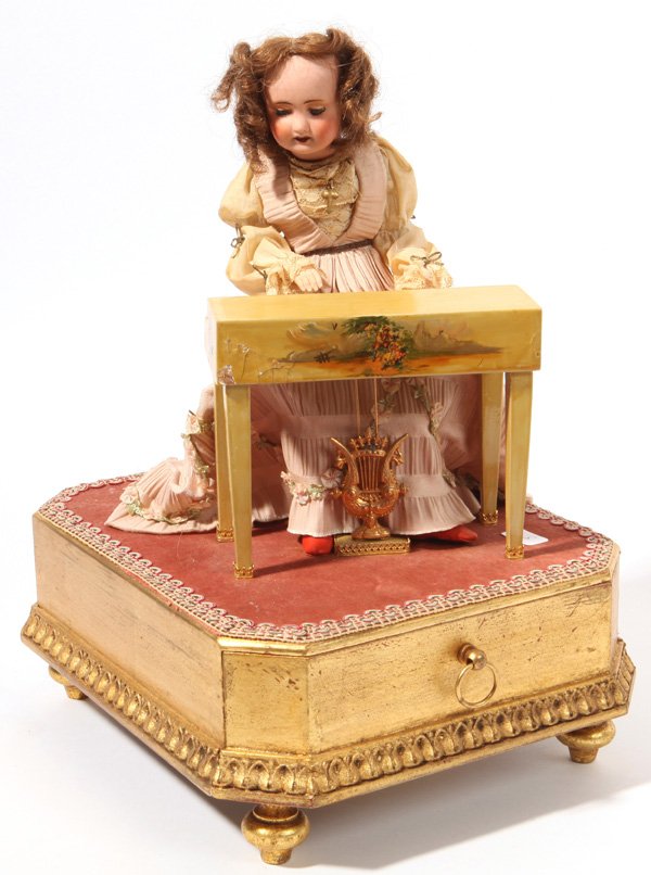 French Musical Automaton Jewelry Case: With French open mouth bisque socket-head doll in original pink and lace dress with bisque forearms, seated at a Vernis-Martin style decorated harpsichord with cylinder box housed in gilt wood box bas