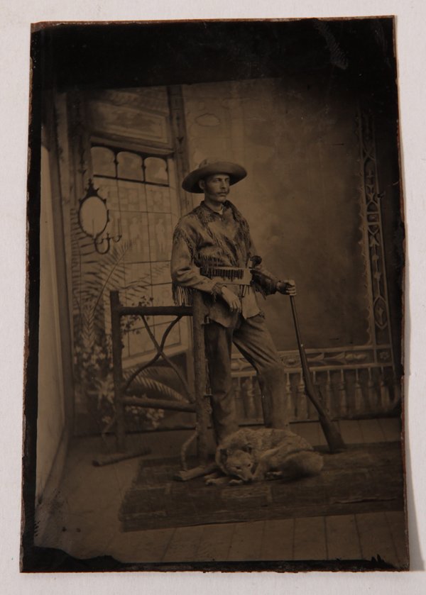 Tintype Portrait of Western Hunter: A very nice, circa 1870 tintype cdv sized full length portrait of a young man dressed in buckskin jacket and broad brimmed hat and holding his carbine rifle, which appears to be a trapdoor Springfield