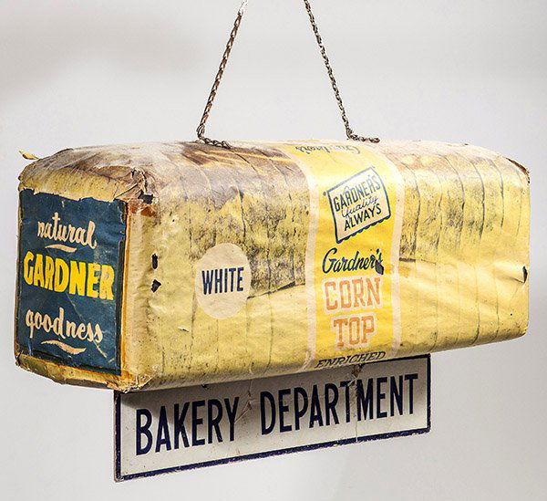 Rare Hanging Gardener's Bread Advertising Sign: In the form of a bagged loaf of bread with printed label "Gardener's Corn Top Enriched White Bread", with orignal chain hanger and hanger below reading "Bakery Department", 26" long x 9" wide and high