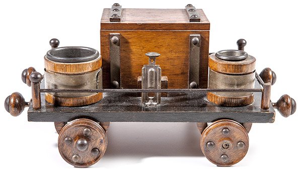 Folk Art Railroad Car Cigar Stand: Oak and steel in the form of a tender car with lidded box on top for cigars, barrel of matches and second barrel for spent matches and cigar cutter mounted at side, original varnish finish, 8 1/2 x 12