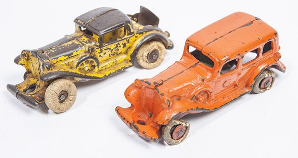 TWO CAST IRON AUTOMOBILES: including a sedan in orange over original green painted finish with white hard rubber tires, 1 1/2 x 5 x 1 3/4" high; plus a touring car with working rumble sesat in original yellow painted finish, 1 