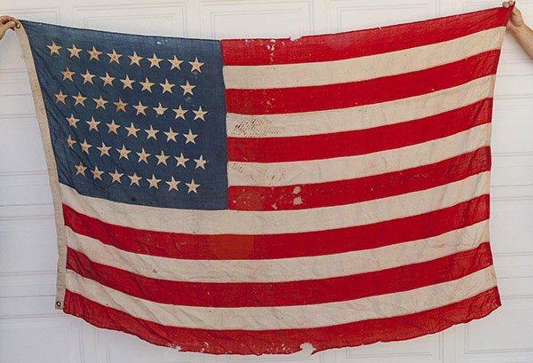 45 Star U.S. Flag: Worsted wool with canton pattern of 8-7-8-7-8-7 (45), with five pointed cotton stars sewn to each face, machine sewn fly with canvas hoist with two brass gommits, 54 x 84 inches.