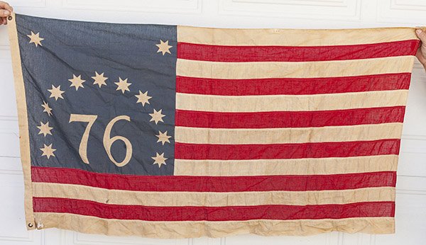 U.S. Centennial 13 Star Flag: Linen with printed canton having large 76 in center with eleven eight-pointed stars arched above, Machine sewn fly, canvas hoist with two brass grommits, 32 x 56 inches.