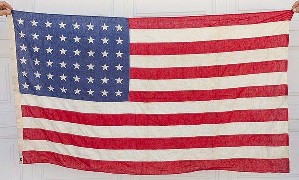 WWII U.S. Flag: with printed canton in six rows of eight stars (48), printed with machine sewn fly, canvas hoist with two brass gommits, 33 x 56 inches.