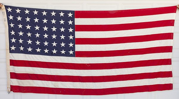 WWI U.S. Garrison Flag: Machine sewn canton & fly in linen with canton pattern of six rows of eight stars (48) with canvas hoist ink stamped Philadelphia Q.M. Depot 5 x 9 1/2. Hoist with two cast steel rings riveted to top a
