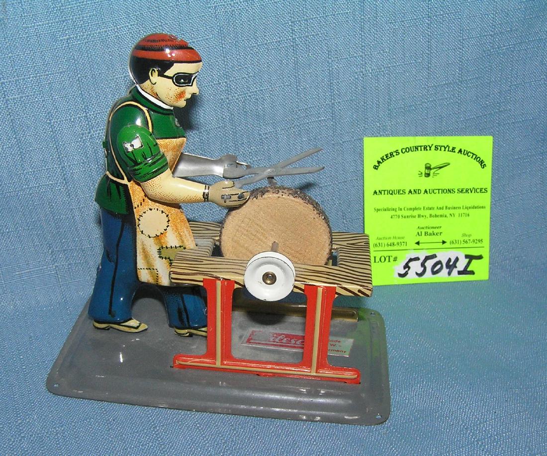 Wilesco all tin mechanical blacksmith toy: Wilesco all tin mechanical blacksmith toy featuring a black smith with goggles sharpening a pair of sissors with sharpening stone made in Germany est. value $80.00-$100.00