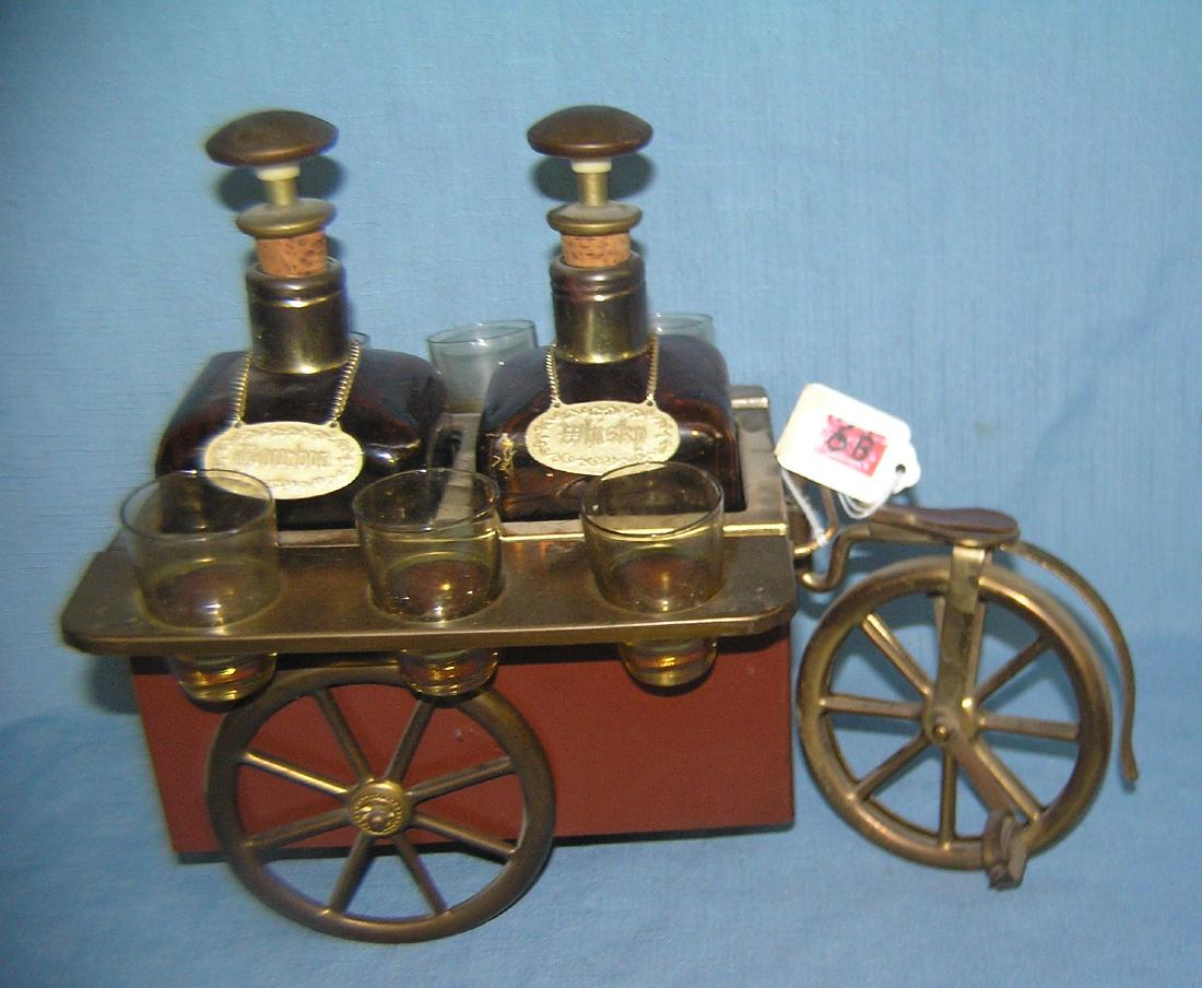 Vintage liquor decanter caddy: Vintage liquor decanter caddy brass, metal and leather in the form of a bicycle themed peddler's cart featuring 2 antique style brown glass decanter with bourbon and whiskey ID tags, musical cart has 