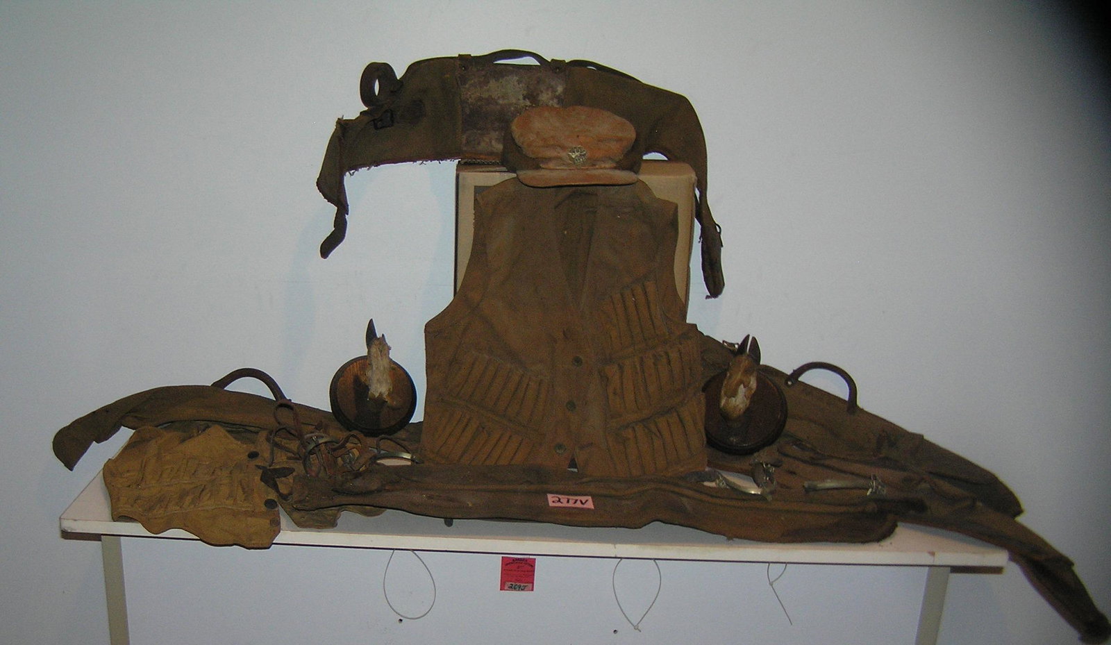 Large group of antique leather and canvas hunting gear: Large group of antique leather and canvas hunting gear includes a pair of early vests, hunter hat with figural buck pin, various gun case, pair of deer hoof wall mounts and 2 pairs of great early stir