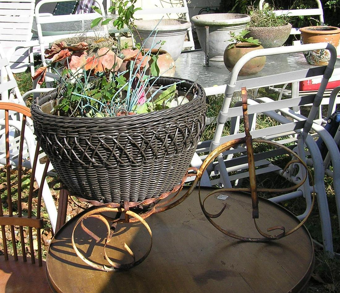 Wrought iron tricycle and planter garden piece: Wrought iron tricycle and planter garden piece 24 inches long by 13 inches wide by 14 1/2 inches high consists of 2 pieces all metal 3 wheel tricycle and a wicker planter est. value $65.00-$75.00