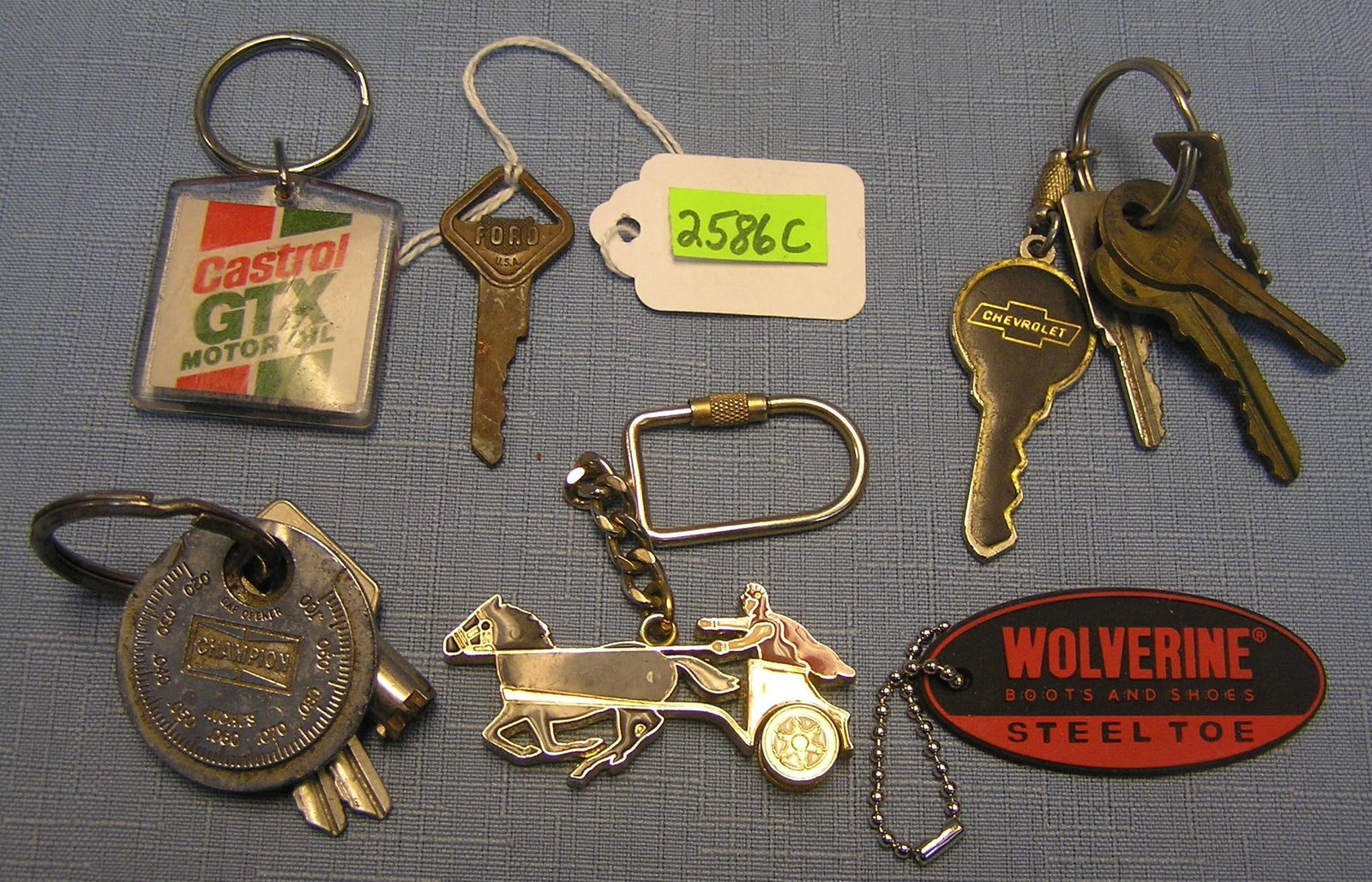 Group of 6 advertising and automotive keys: Group of 6 advertising and automotive keys and key chains includes Wolverine, painted chariot with rolling wheels, Castro GTX motor oil, Campion, Gap gage advertising piece, Chevrolet and an antique F