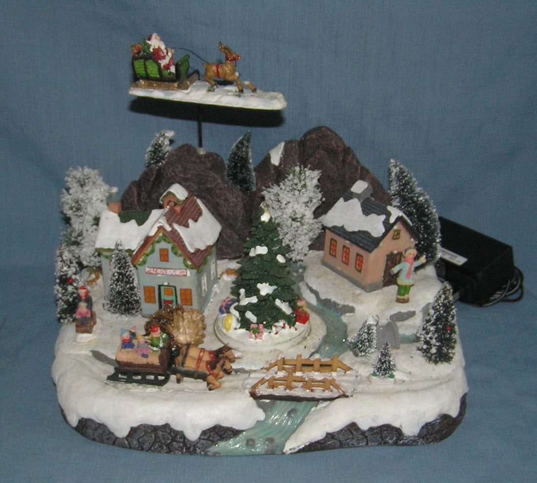 Electric illuminated holiday themed Christmas village: Electric illuminated holiday themed Christmas village lights up and Christmas tree spins est. value $65.00-$75.00