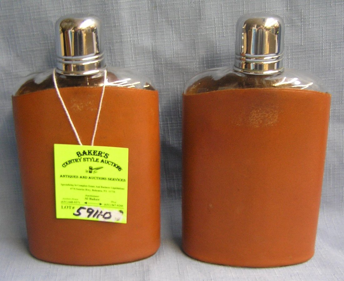 Pair of glass drinking flasks with leather covers: Pair of glass drinking flasks with leather covers and chrome caps est. value $50.00-$75.00