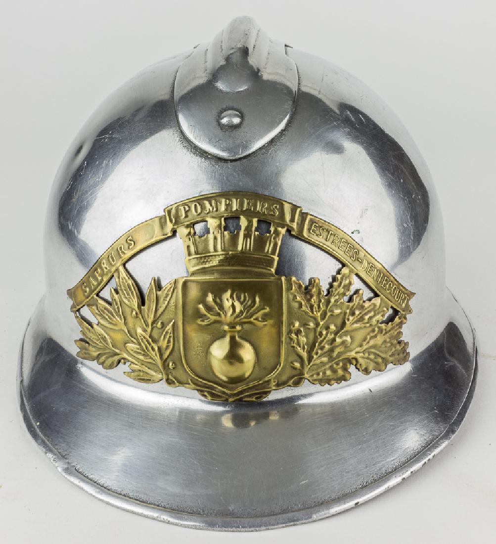 FRENCH FIREMAN'S PARADE HELMET: FRENCH FIREMAN'S PARADE HELMET World War II-era M26 "Adrian" helmet, with a metal comb affixed to the crown with four pins. The shell bears a bright polished finished overall, and bears a brass plaque