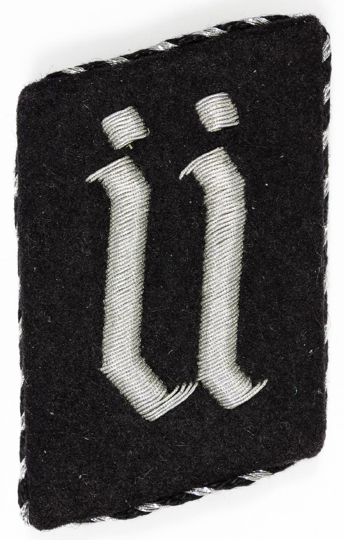 SS DACHAU TRAINING CAMP COLLAR TAB: SS DACHAU TRAINING CAMP COLLAR TAB Rare detachable black felt collar tab, 1 3/4" x 2 3/4", on a metal backing fitted with four screw-tipped posts, to facilitate removal. A Germanic letter "U" is embro
