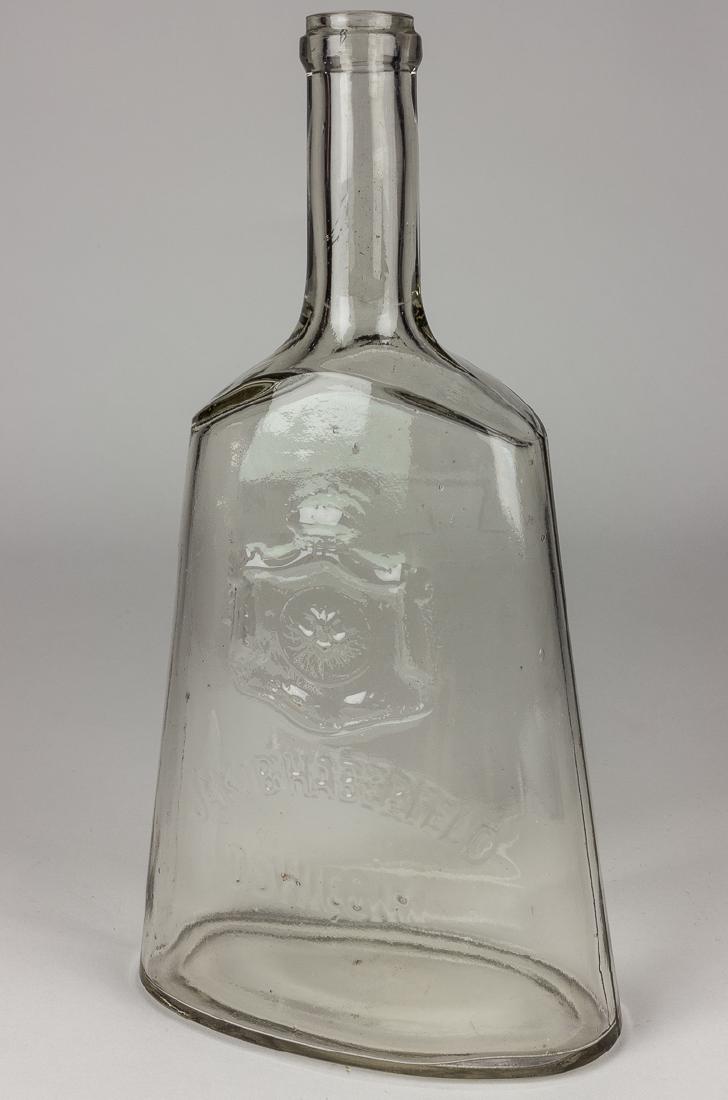 JAKOB HABERFELD LIQUOR BOTTLE FROM AUSCHWITZ: JAKOB HABERFELD LIQUOR BOTTLE FROM AUSCHWITZ Clear glass bottle manufactured for the Jakob Haberfeld vodka and liquor factory at Oswiecim (later Auschwitz), approx. 11 1/4" x 5 1/4" dia., bearing in r